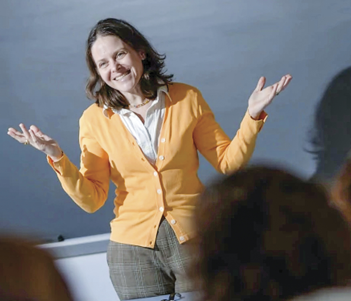 white woman with brown hair in gray pants and yellow cardigan with white button down shirt