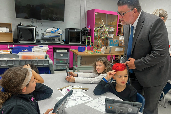 man with young students at table