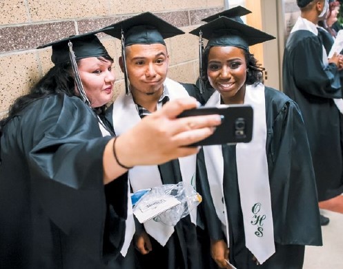 Three seniors pose for a selfie in their caps and gowns