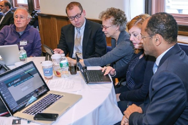 A group of teachers collaborate on their laptops around a table