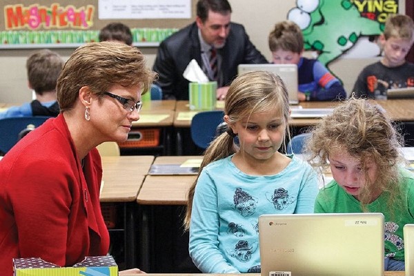 Heather Beck with young students using laptop