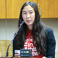 Chloe Sorensen addresses a room from a microphone