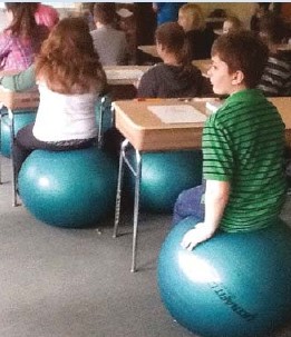 Kids sit at desks on blue exercise balls instead of chairs