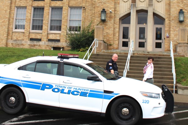 A police car at the front entrance to a school with an officer