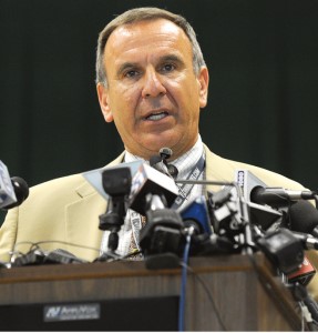 Joseph Erardi speaks at a podium with many microphones