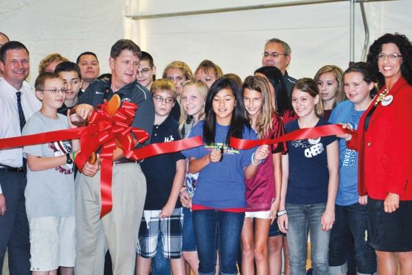 Students gather around a red ribbon to celebrate the reopening of school