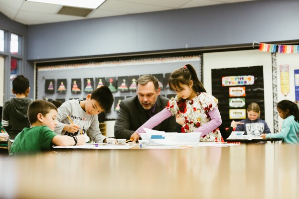Coby Dennis assists three students at a classroom table
