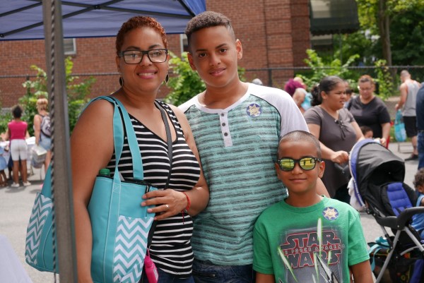 A woman and two adolescents smile for the camera at an outdoor event