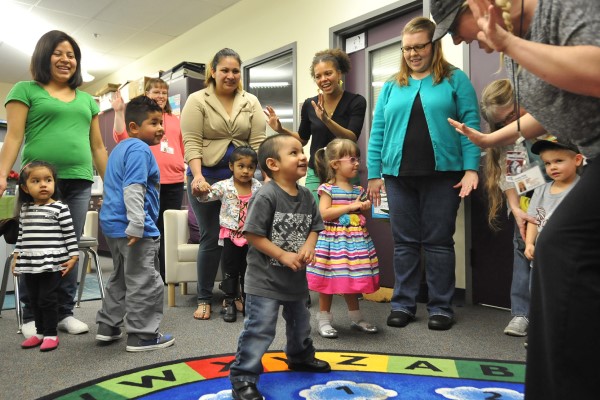 A young student dances in the middle of a circle of adults and other students