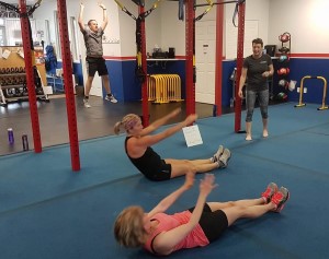 Two people exercising on the floor in a gym