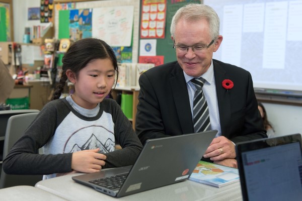 John Malloy sits next to a student working on a laptop