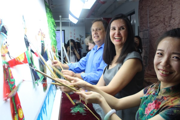 Three educators hold shadow puppets up to a puppet theater
