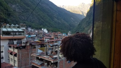 A student looks out of a window over a city in Peru