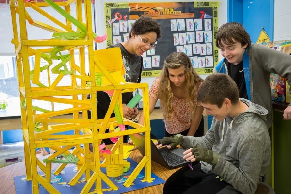 Students work on a project together next to a yellow sculpture