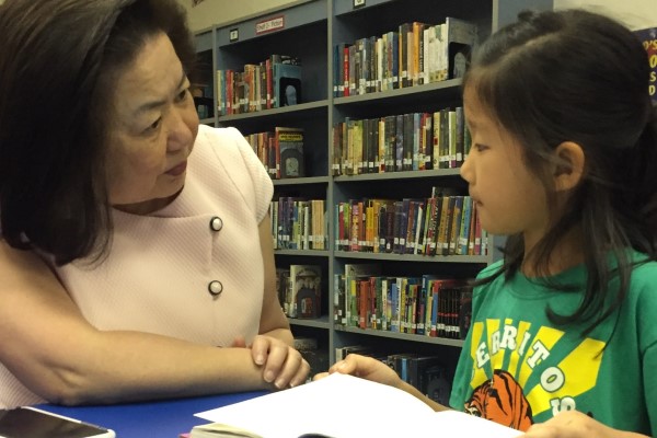 Mary SIeu speaks with a student in a library