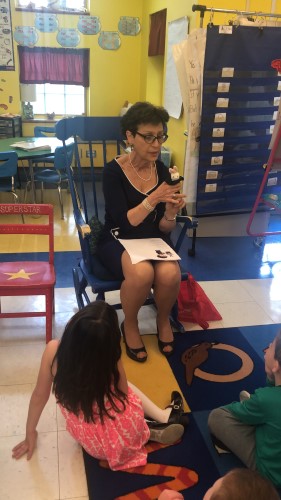 Nancy Lubarsky reads to two students and wears a cow finger puppet