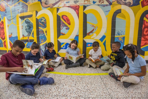 seven students reading in front of a colorful wall