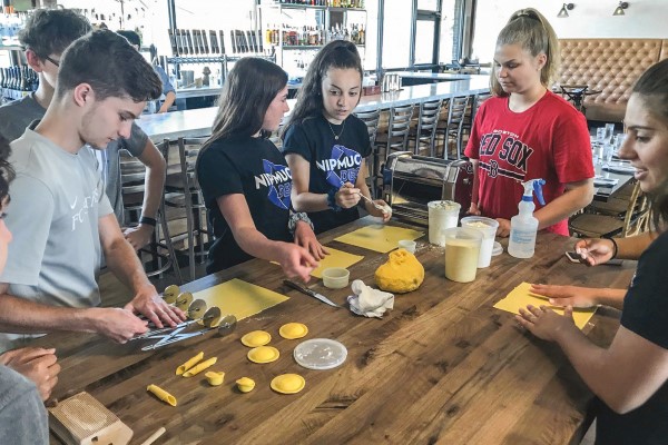 Seven students prep a cooking assignment around a table together