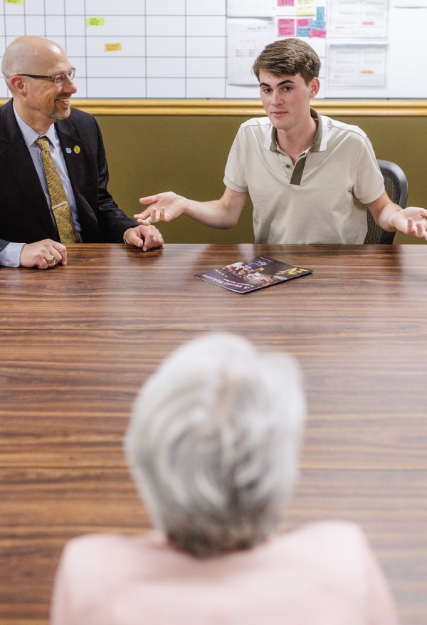 Noah Percy speaks with DT Magee and another administrator at a board room table