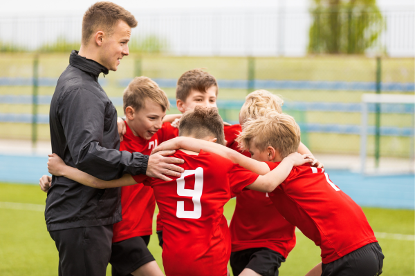 coach with group of young boys in red jerseys huddling