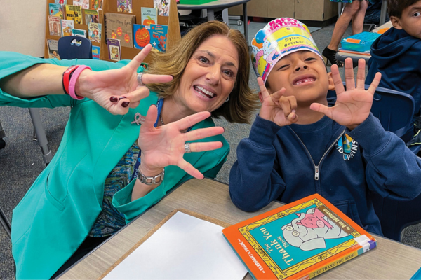 Julie Vitale and young student smiling at camera holding up 7 fingers