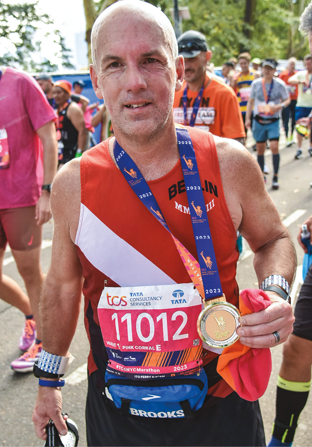 A white man in running clothes wearing a medal around his neck