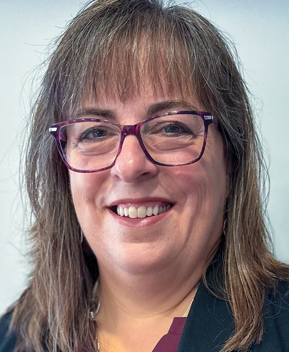 Headshot of white woman with brown hair and bangs wearing glasses