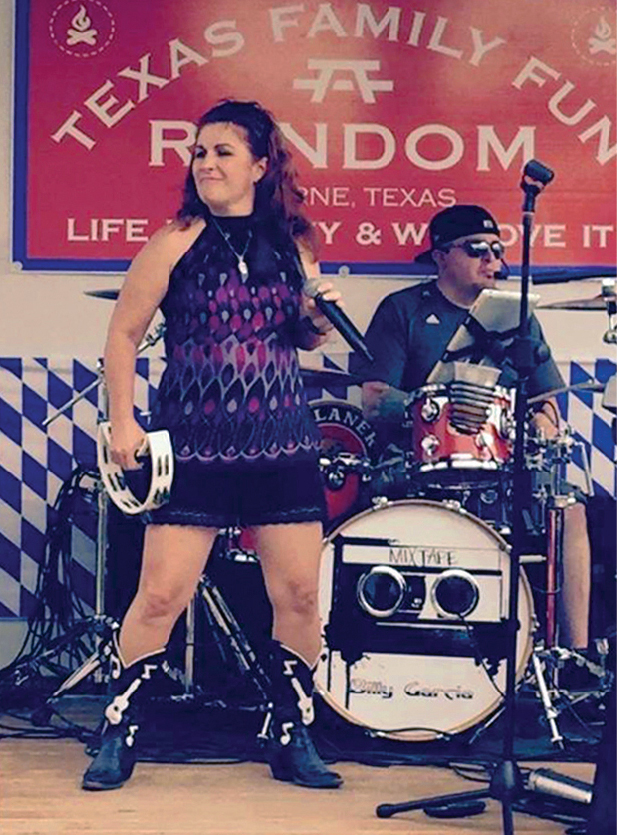 Woman in a dress with tambourine on stage in front of drummer and drumset