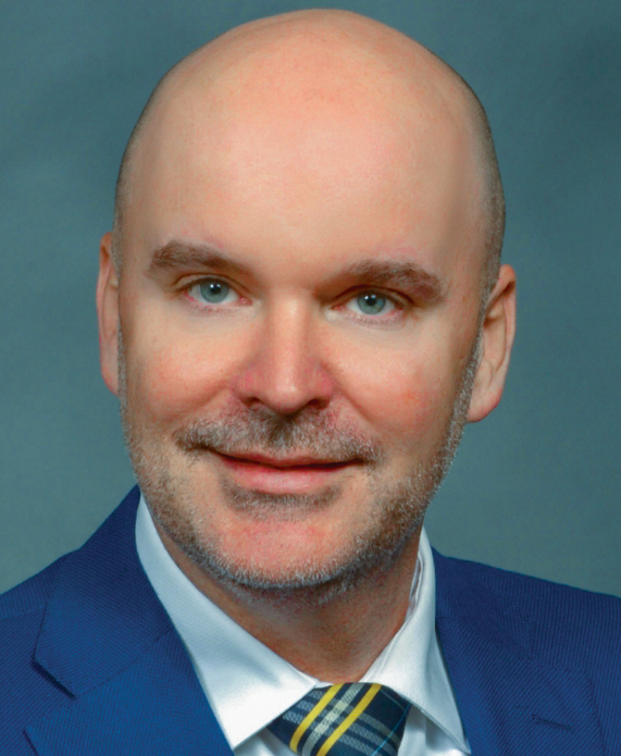 Headshot of a bald white man wearing a blue suit