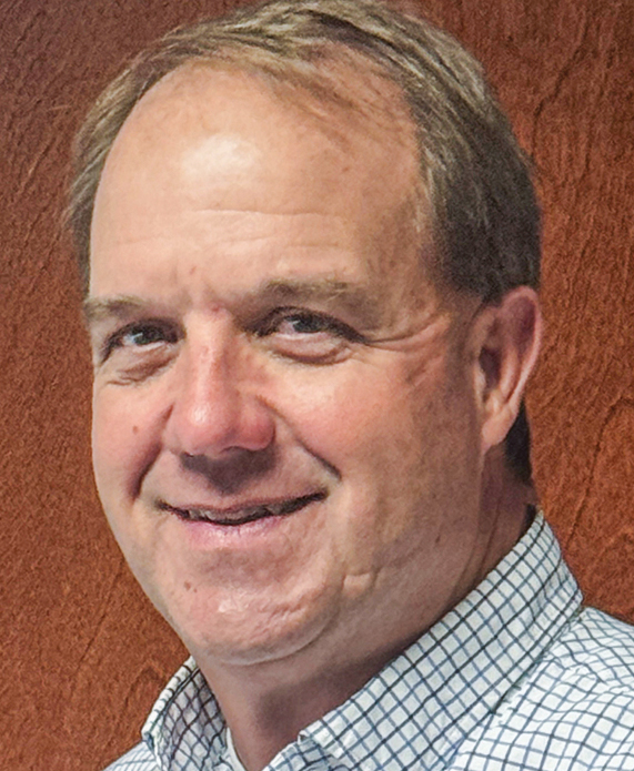 Headshot of white man smiling wearing checkered button up shirt