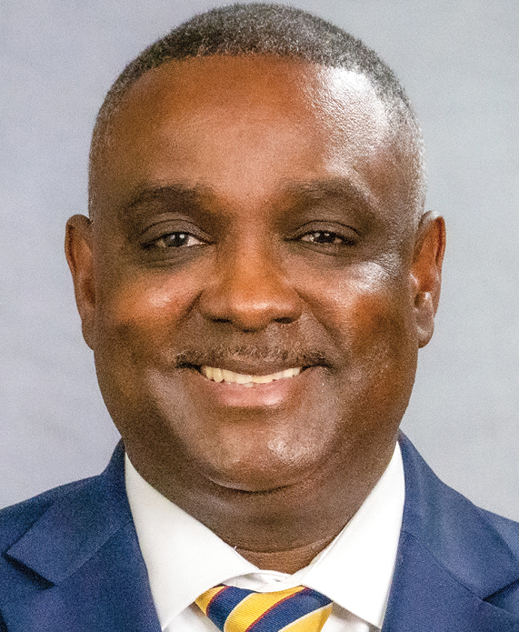 A Black man smiling wearing a suit and striped tie (headshot)