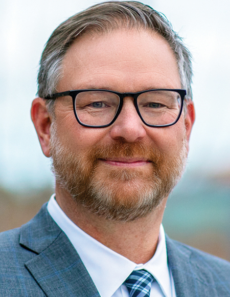 Headshot of a man wearing glasses and a suit