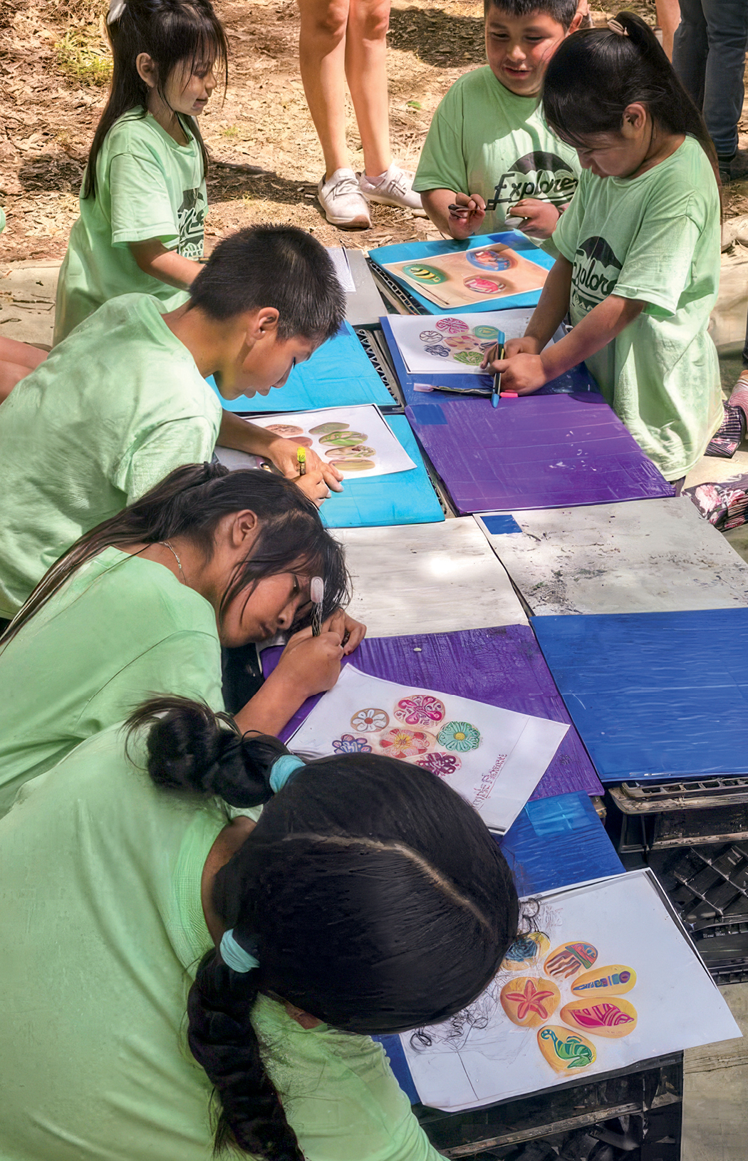 A group of students in green t-shirts works on a project