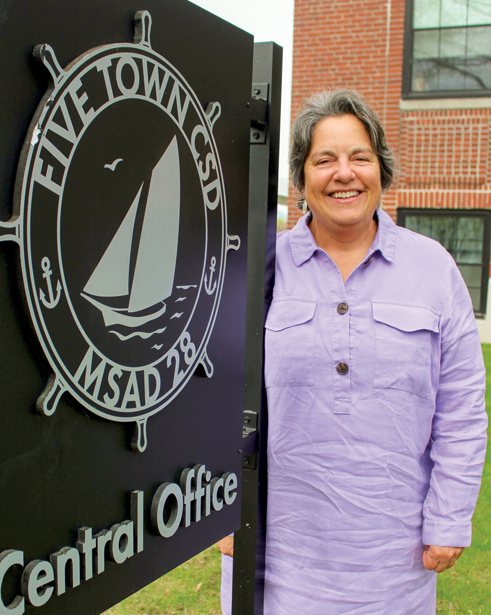 A woman in purple dress standing by Five Town CSD Central Office sign