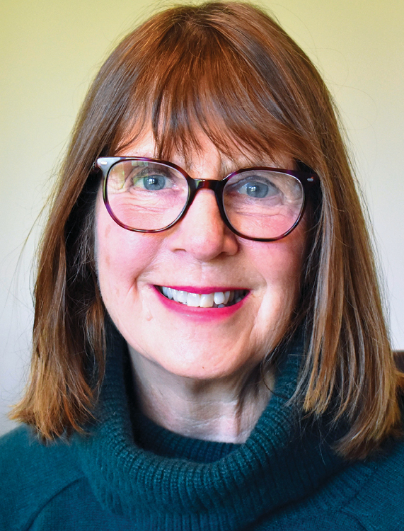 Headshot of white woman wearing glasses and green turtleneck