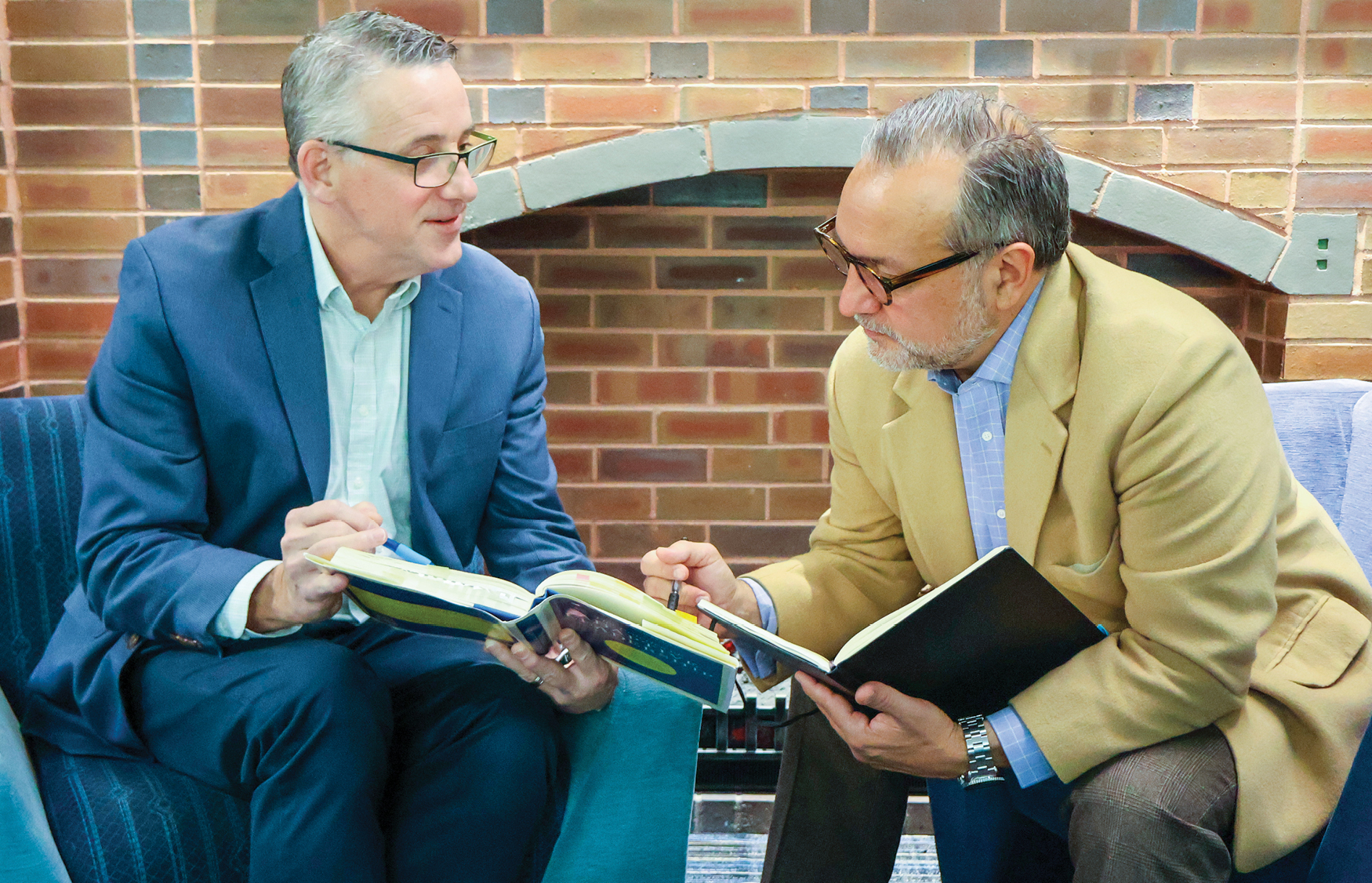 Two men sitting looking at books together