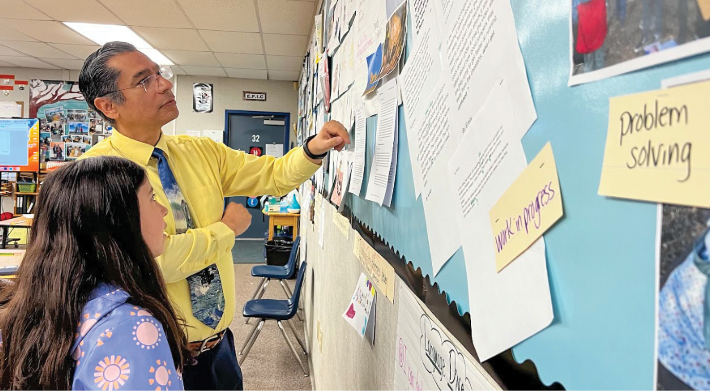 A man standing at a classroom board with a girl