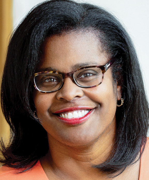 Headshot of a Black woman smiling wearing glasses