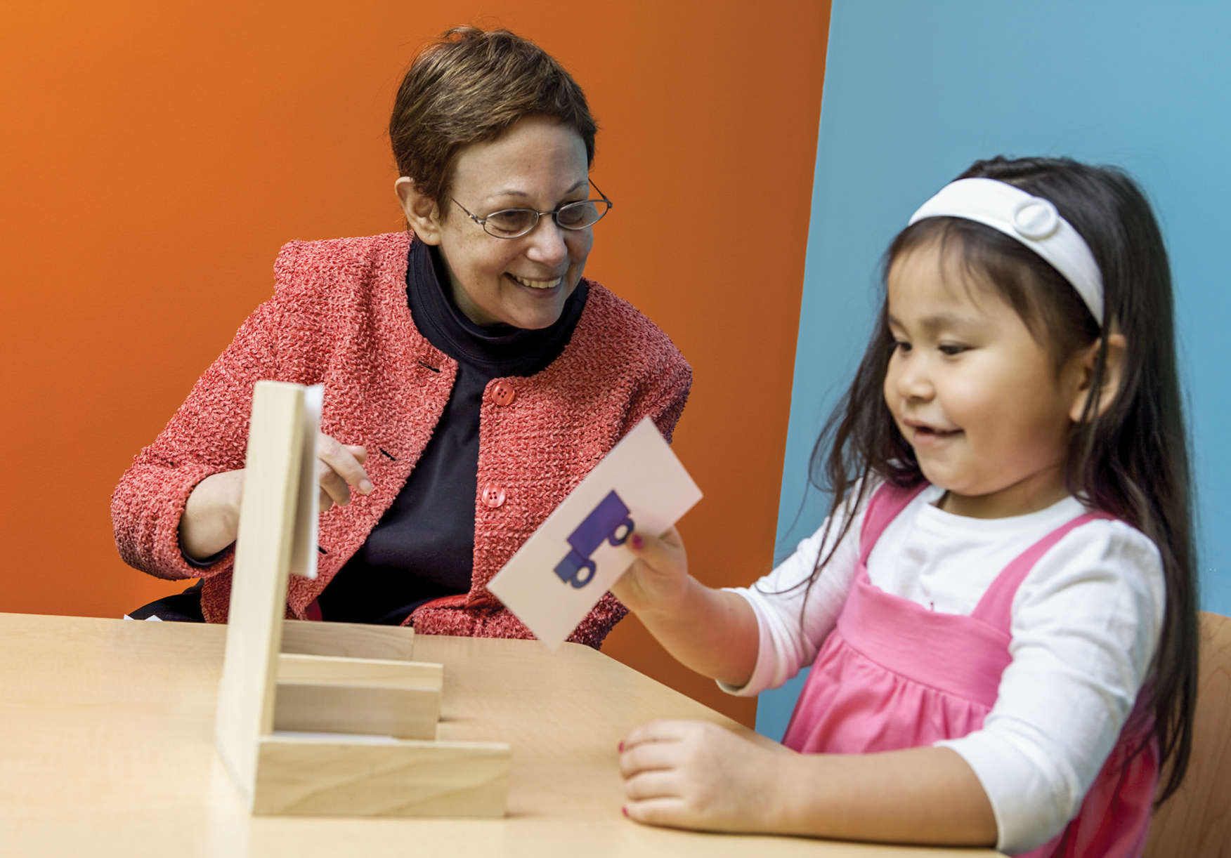 A woman at table playing with blocks with elementary school girl