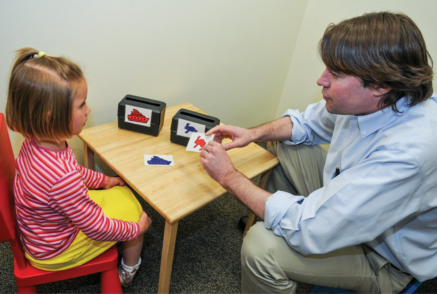 A man sitting at table with young girl looking at cards