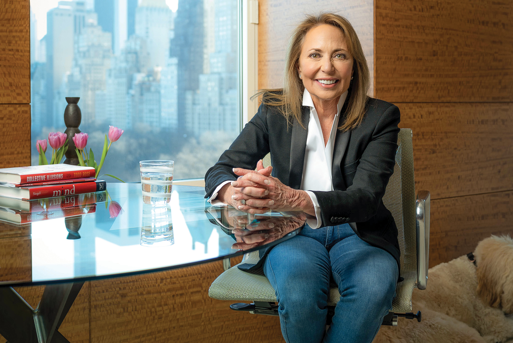 A brunette white woman sitting smiling at glass table
