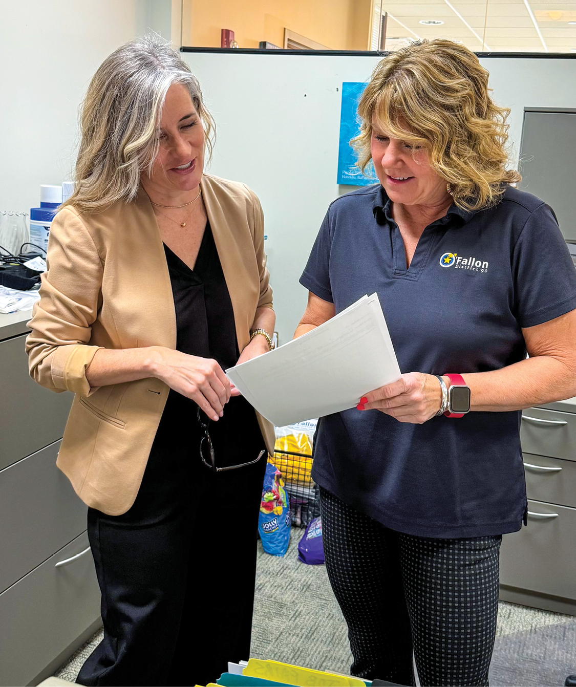 Two women standing and looking at a paper together