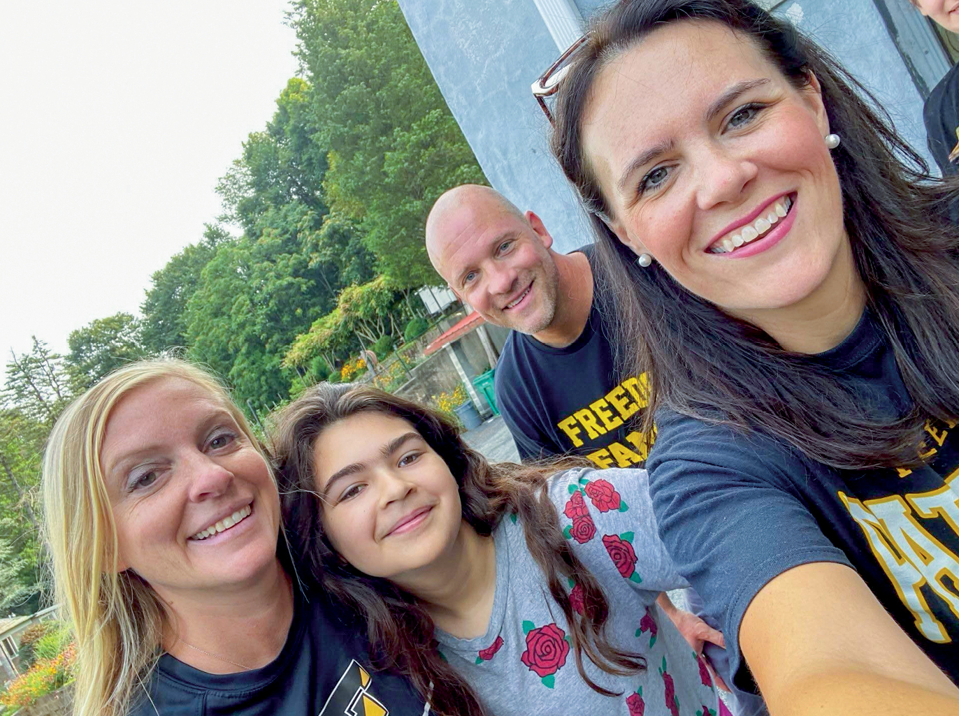 A woman with brown hair selfie with parents and a student