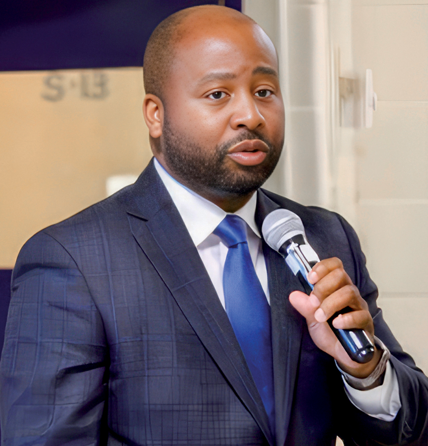 27-Minus-upsampled A Black man in suit holding microphone and talking