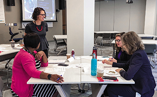 Amy Gallo (standing), author of Harvard Business Review’s Guide to Dealing with Conflict, checks in with participants at a workshop she led on conducting difficult conversations with coworkers.