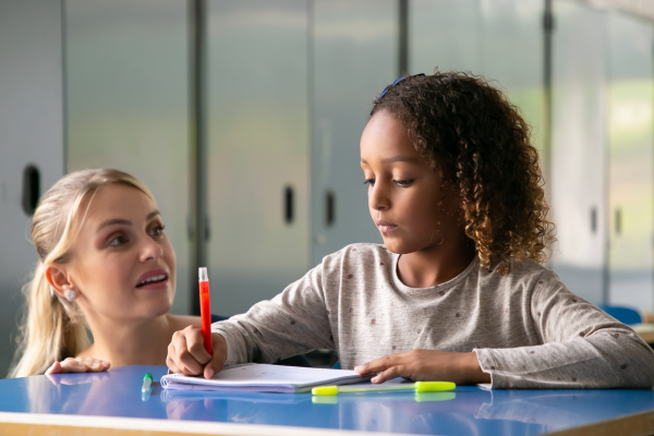 Educator with a student working at a desk