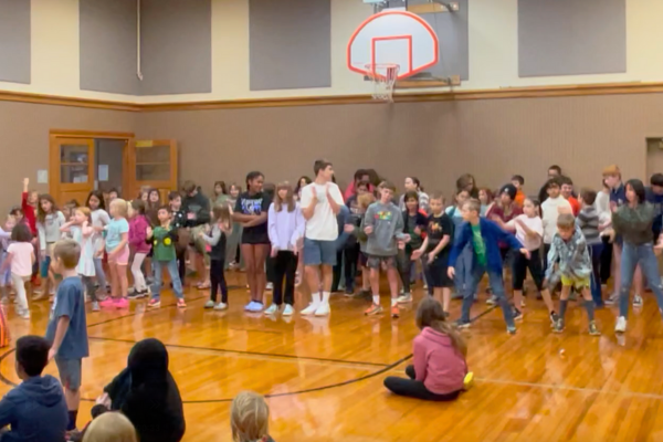 Students and staff gathered in gymnasium at school to sing and dance.