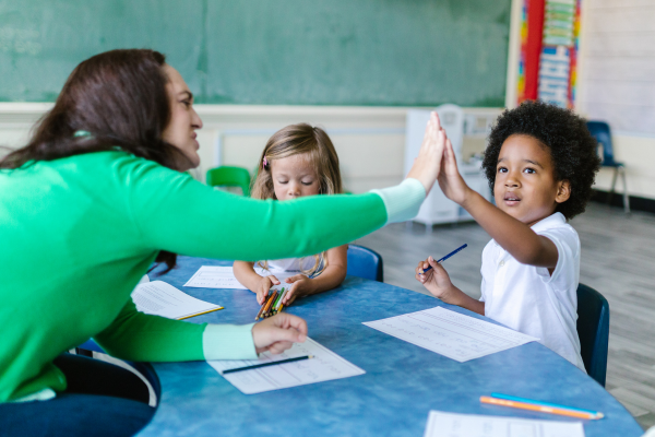 Teacher high fives a student in a classroom