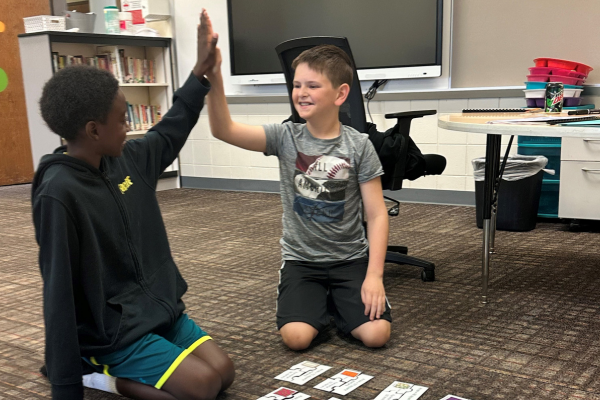 Two children giving each other a high five after completing a task.