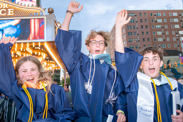 Three students cheering happily at graduation.